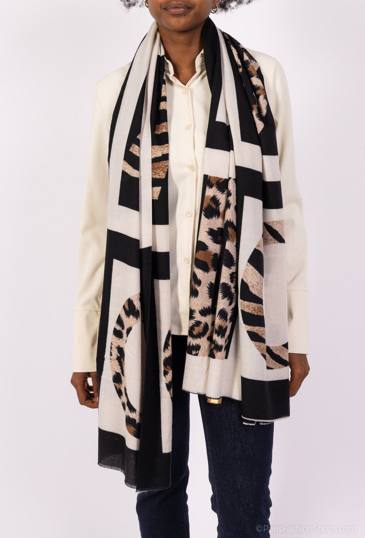 Person wearing a long, patterned scarf with geometric and animal print designs on a white background.