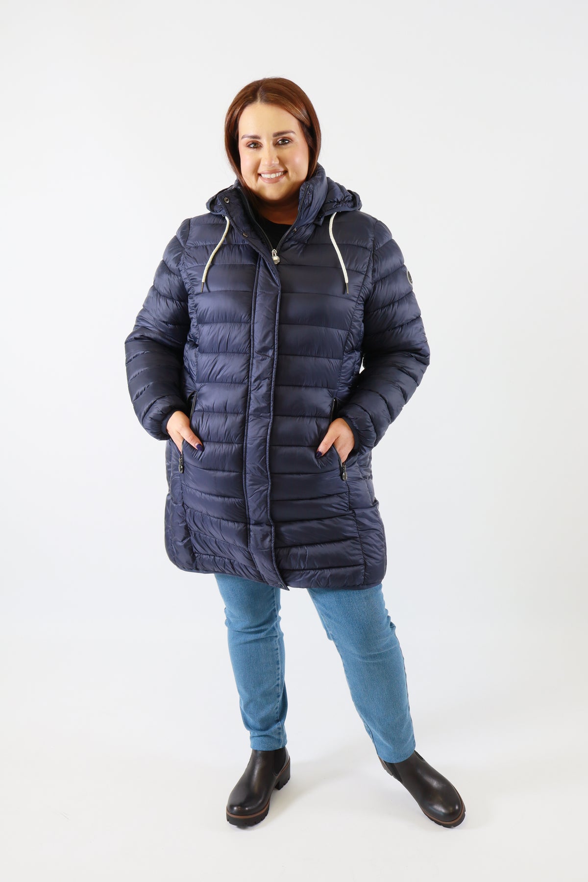 Person wearing a blue puffer coat and jeans on a white background