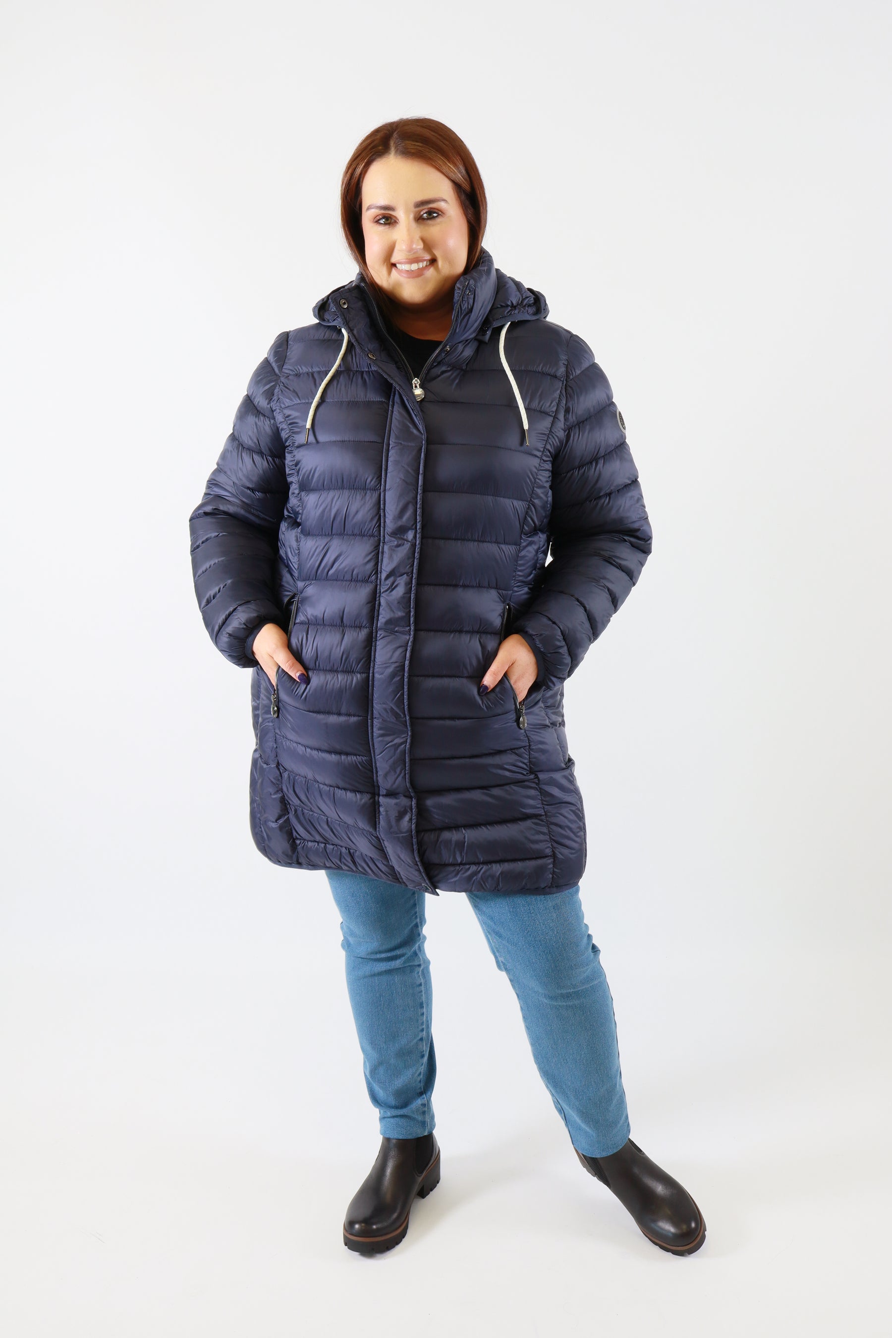 Person wearing a blue puffer coat and jeans on a white background