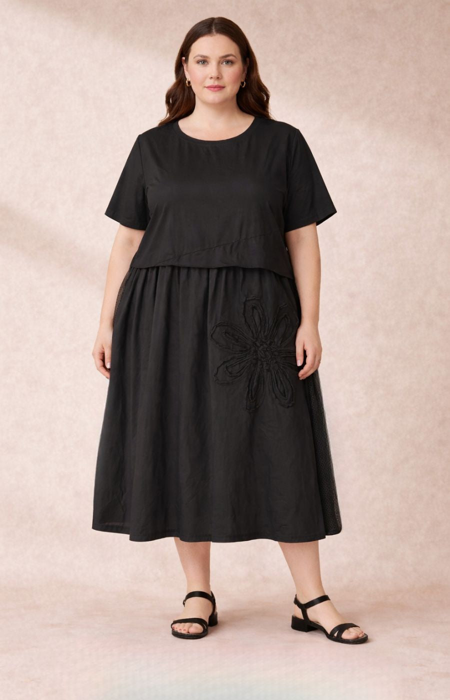Geneva Dress in Black, a cotton dress with an A-line shape, round neckline, short sleeves, side pockets and a floral applique design on the front
