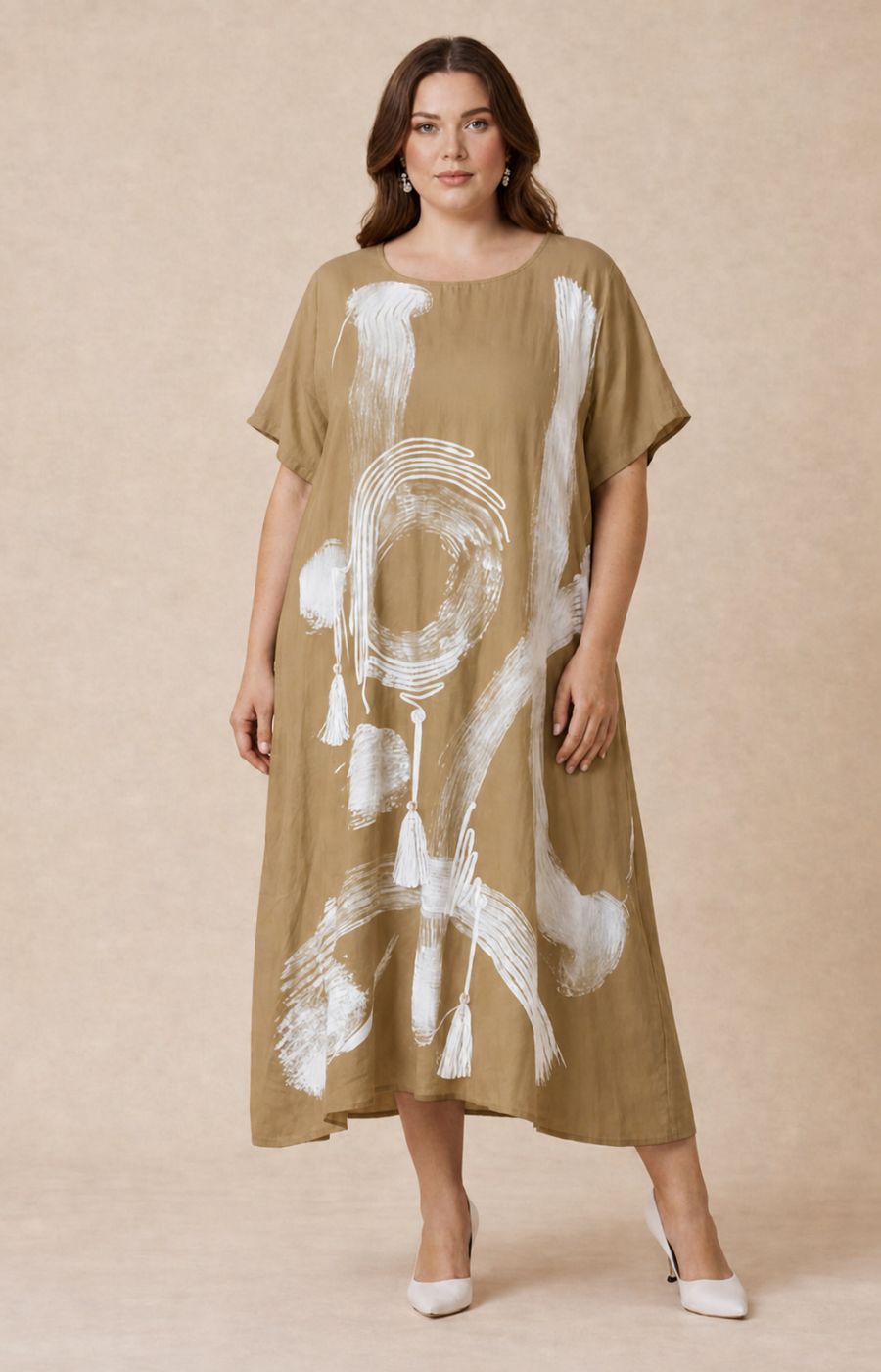 Woman wearing the Giselle Dress in Tan, a beige dress with white abstract patterns on a beige background