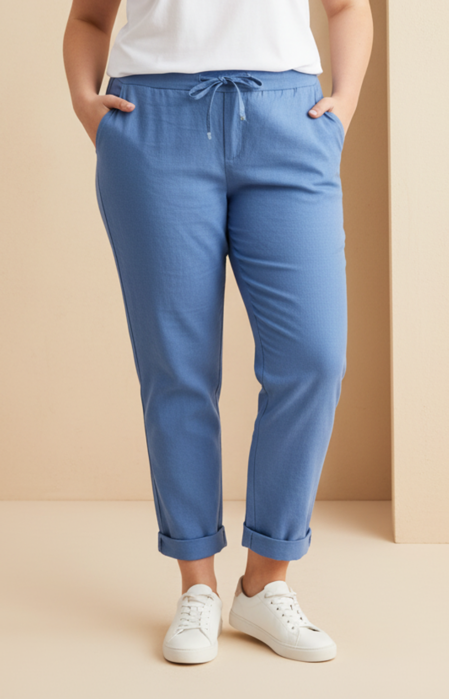 Woman wearing a white t-shirt and blue pants against a beige background