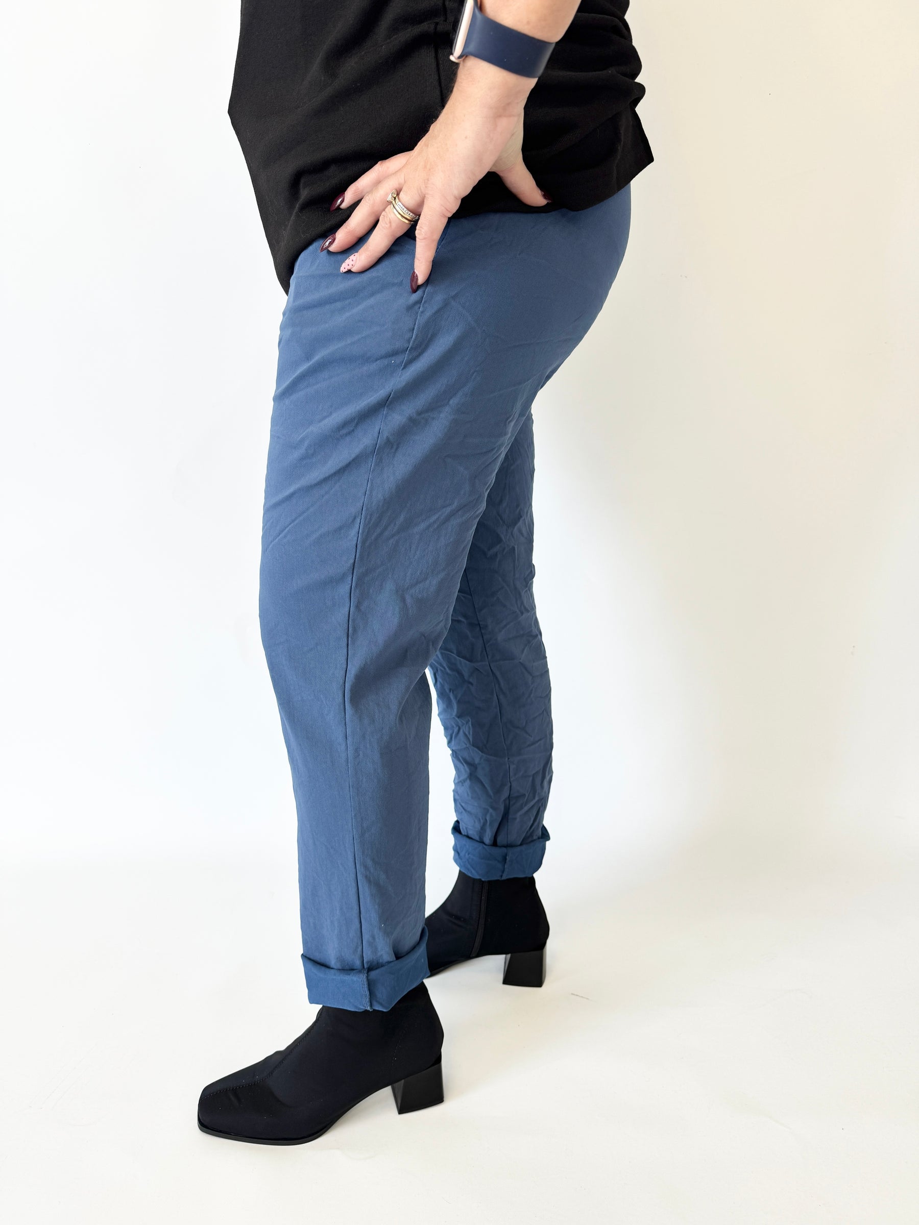 Person wearing blue pants and black shoes on a white background