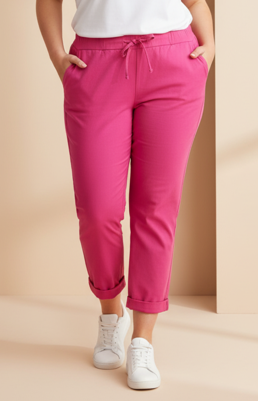 Person wearing bright pink pants and white sneakers on a beige background
