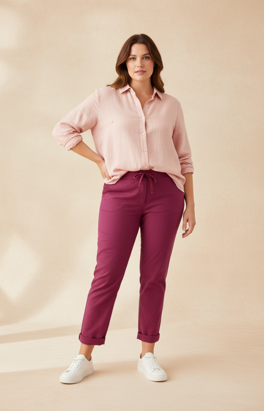 Woman wearing a light pink shirt and wine pants on a beige background