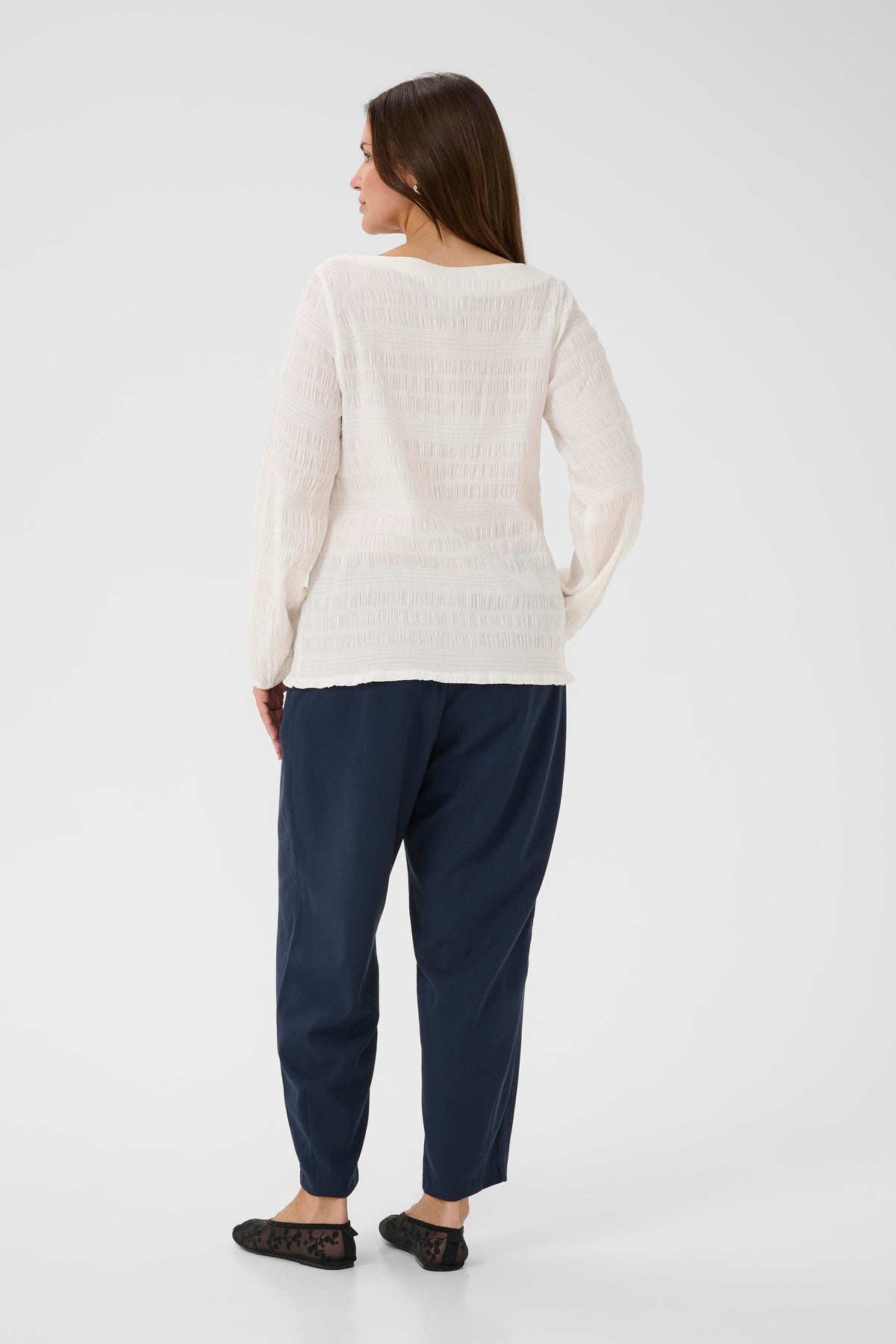 Woman wearing a Kaffe Curve Jourtney Blouse in White and navy pants on a white background