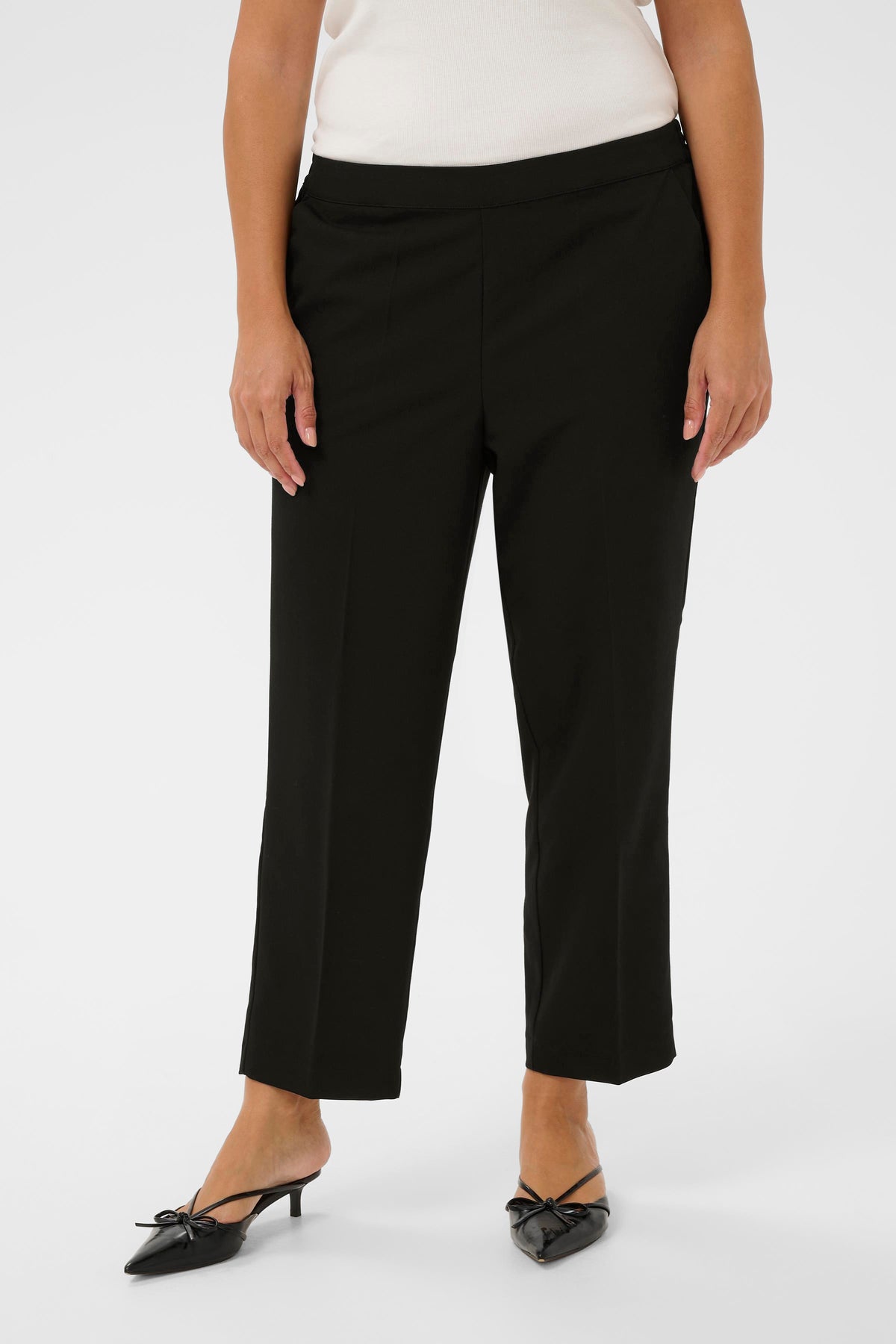 Person wearing black ankle length trousers on a white background