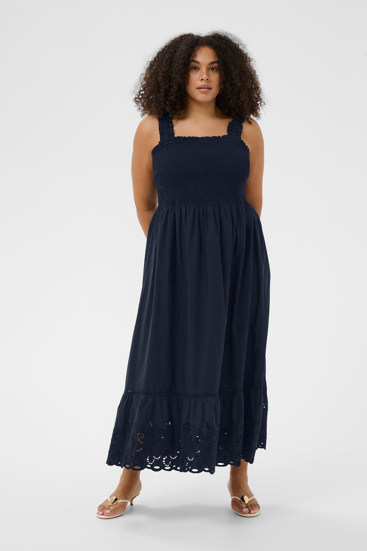 Woman wearing the Kaffe Curve Trudi Dress in Navy, a navy blue dress with lace details on a white background