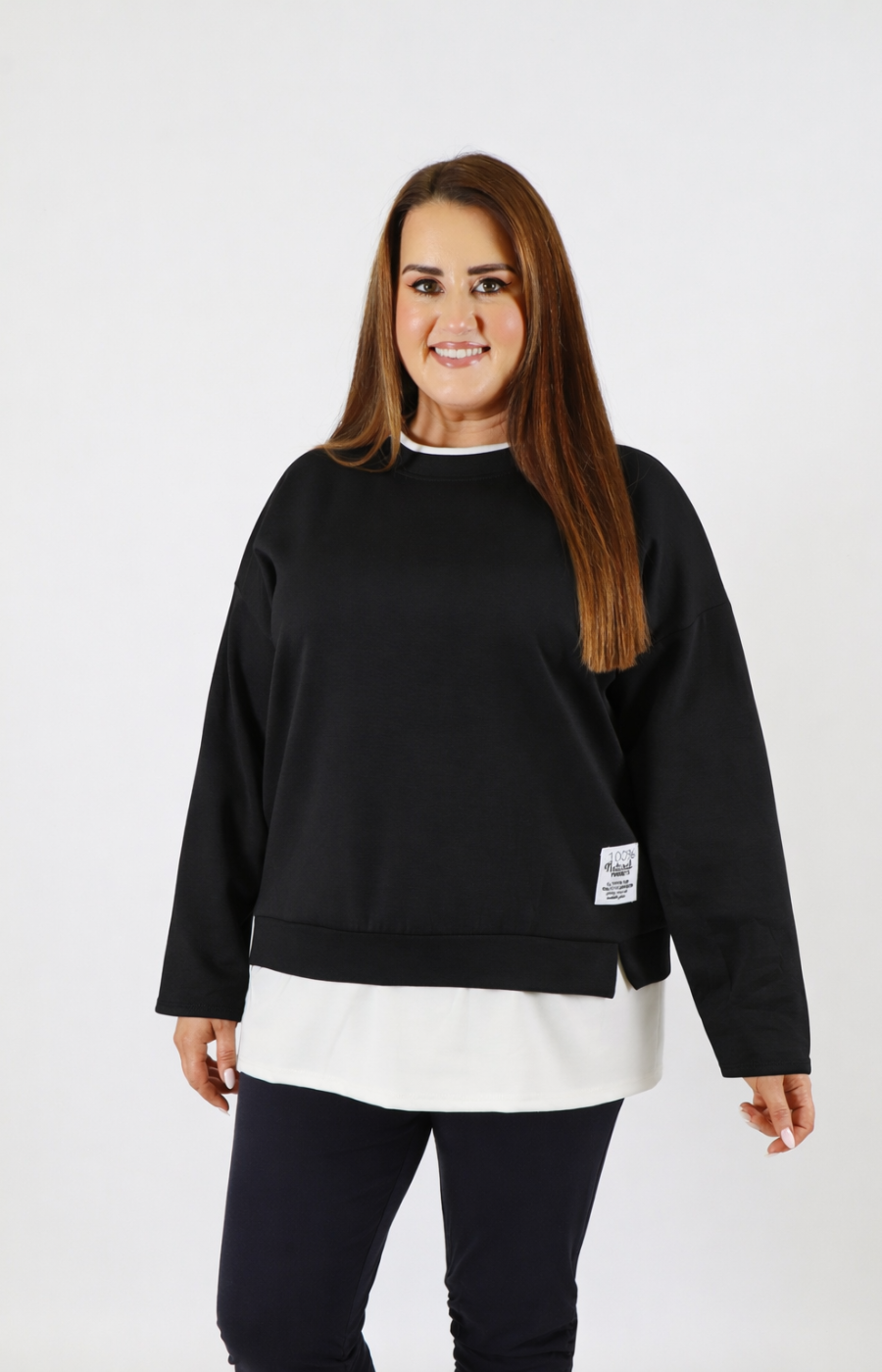 Woman wearing a black sweatshirt with a white trim on a plain background