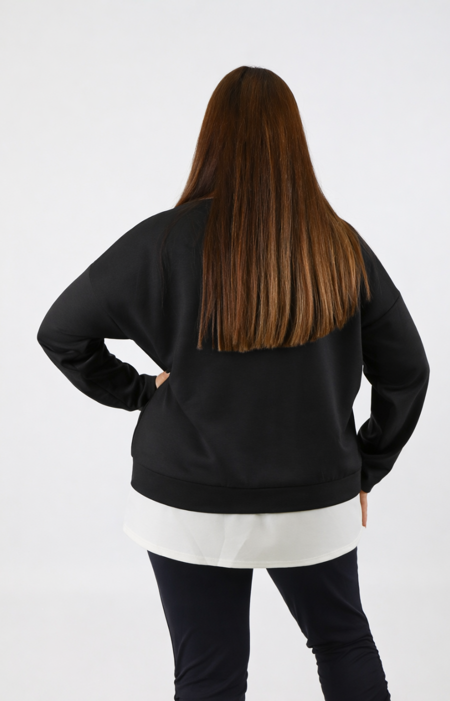 Woman wearing a black sweatshirt with a white trim on a plain background