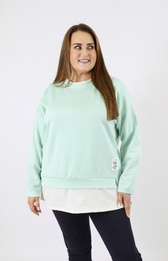 Woman wearing a mint sweatshirt with a white trim on a plain background