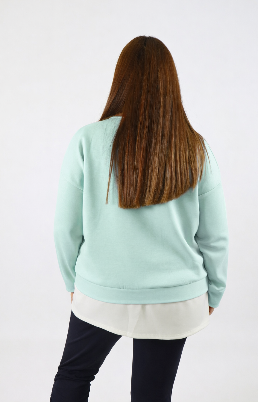 Woman wearing a navy sweatshirt with a white trim on a plain background