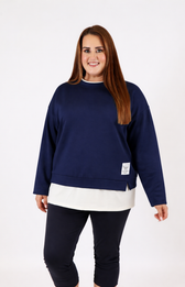 Woman wearing a navy sweatshirt with a white trim on a plain background