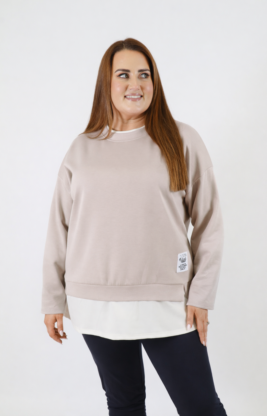 Woman wearing a taupe sweatshirt with a white trim on a plain background
