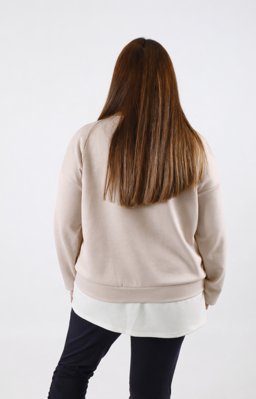 Woman wearing a taupe sweatshirt with a white trim on a plain background