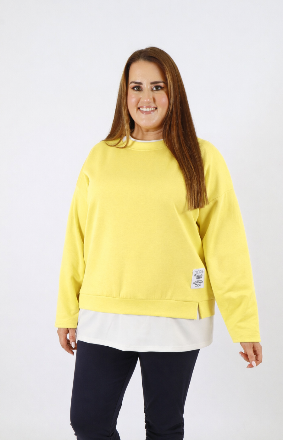 Woman wearing a yellow sweatshirt with a white trim on a plain background