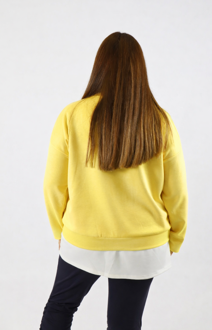Woman wearing a yellow sweatshirt with a white trim on a plain background