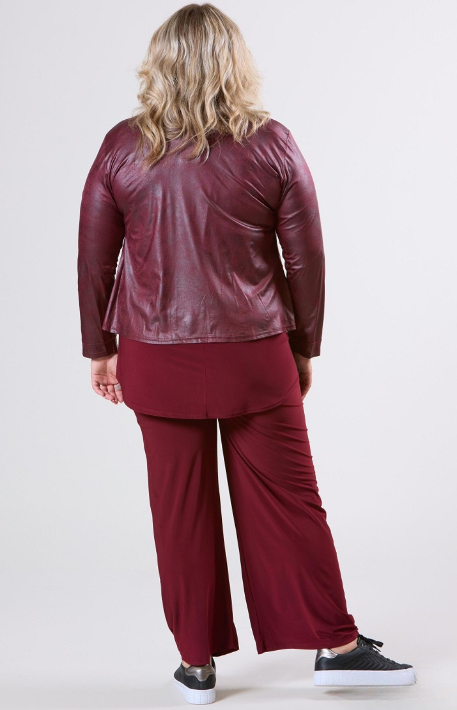 Person wearing a burgundy outfit with a jacket and pants on a white background