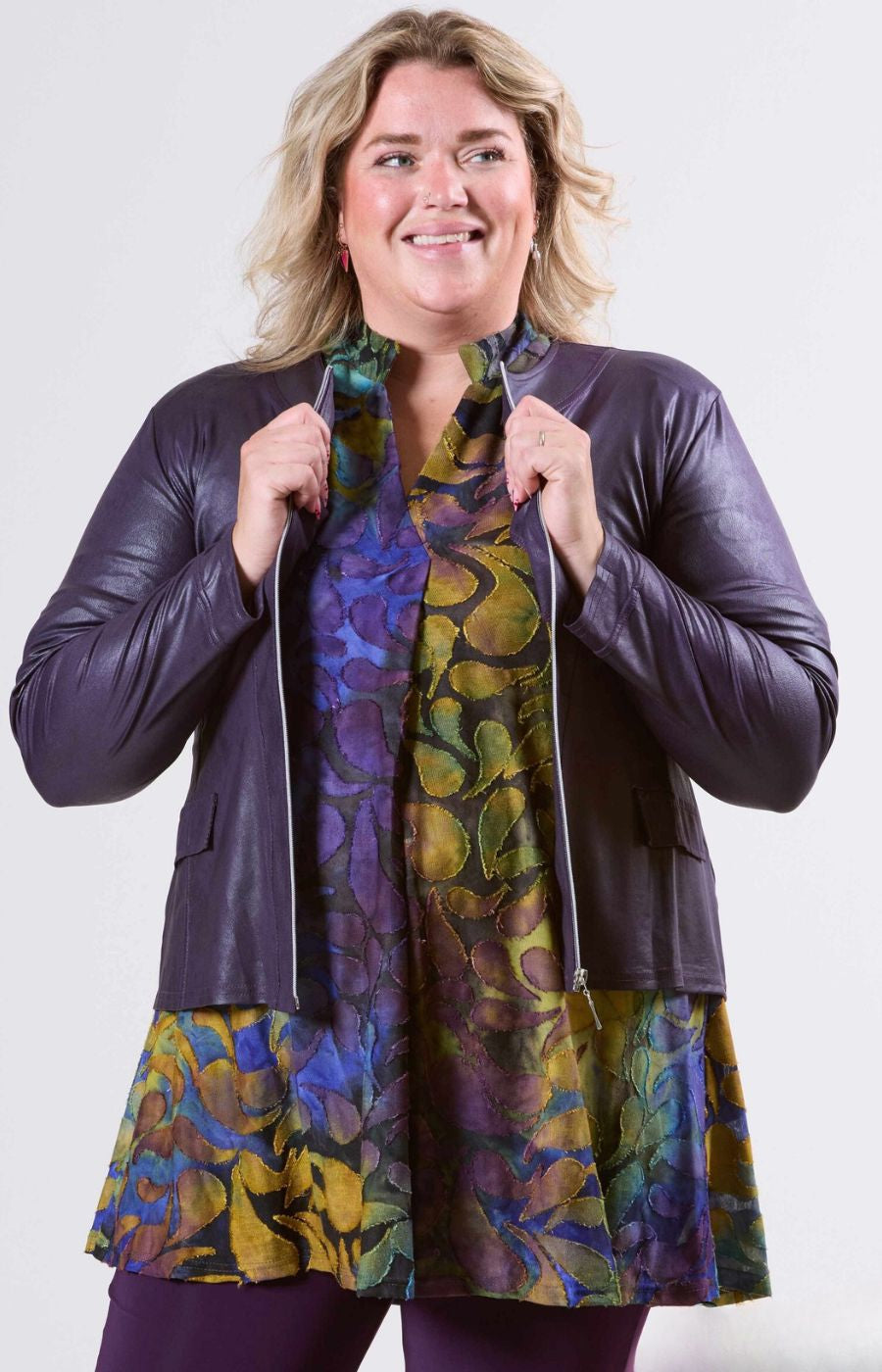 Woman wearing a purple jacket over a colorful dress on a white background
