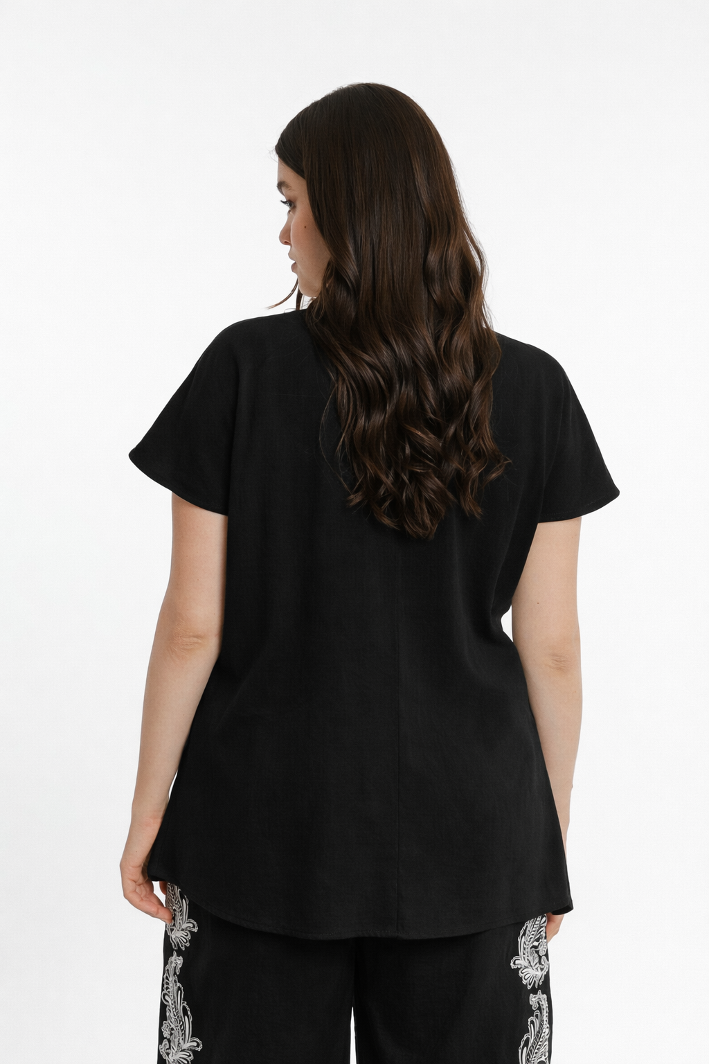 Woman wearing a black top with floral sleeves on a white background