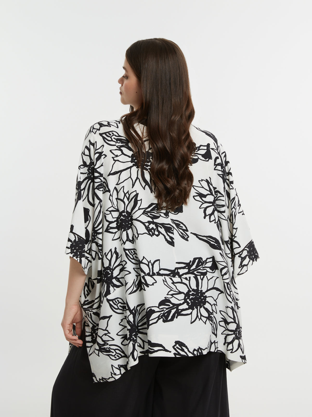 Woman wearing a black and white floral blouse against a white background