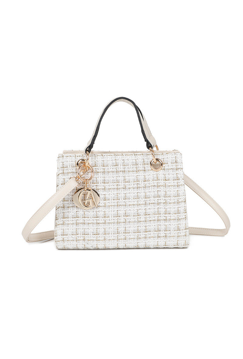 Woven handbag with gold accents on a white background