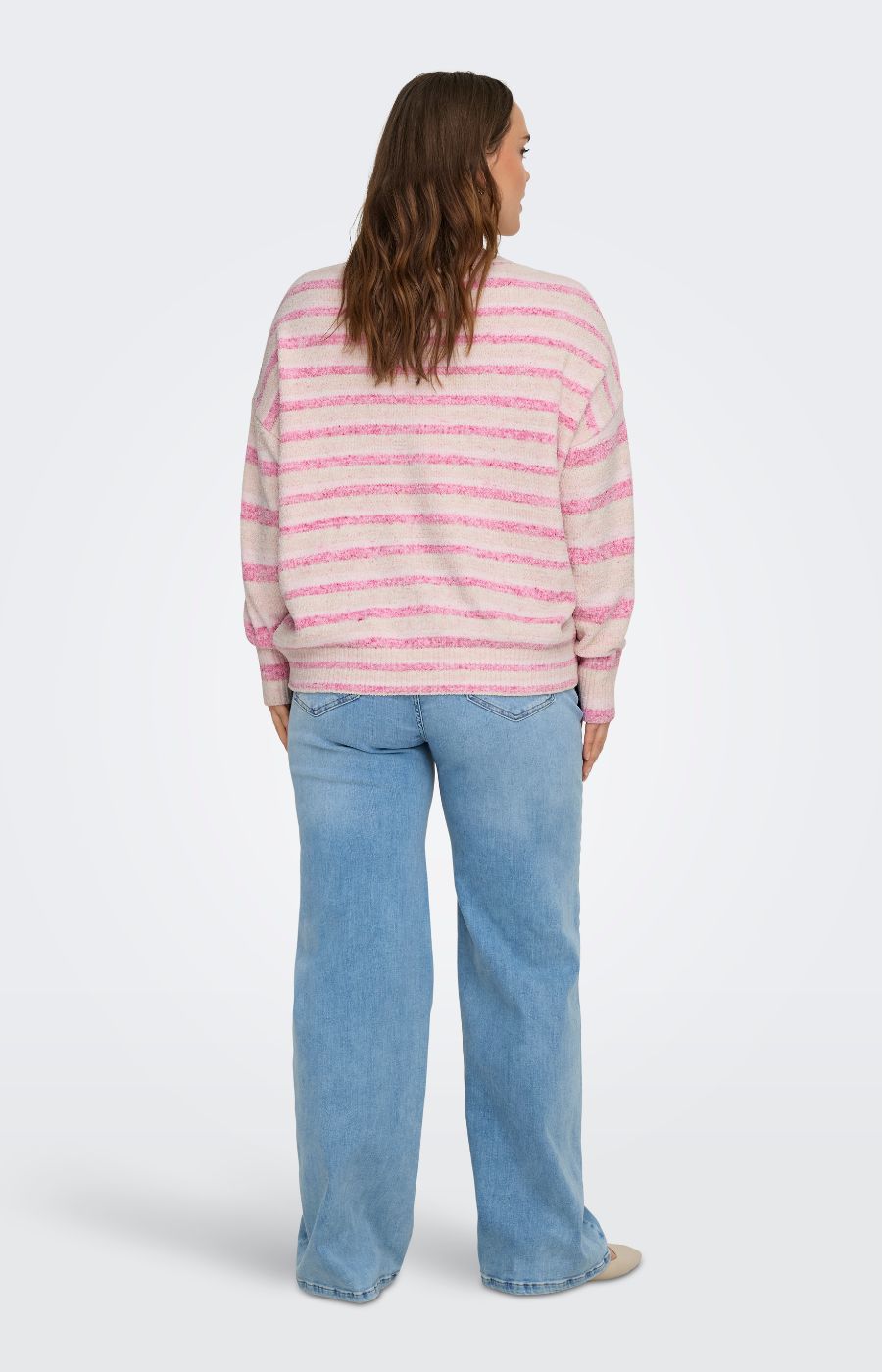 Person wearing the Only Carmakoma Johanna Knit in Pink, a striped sweater with long sleeves and jeans on a white background