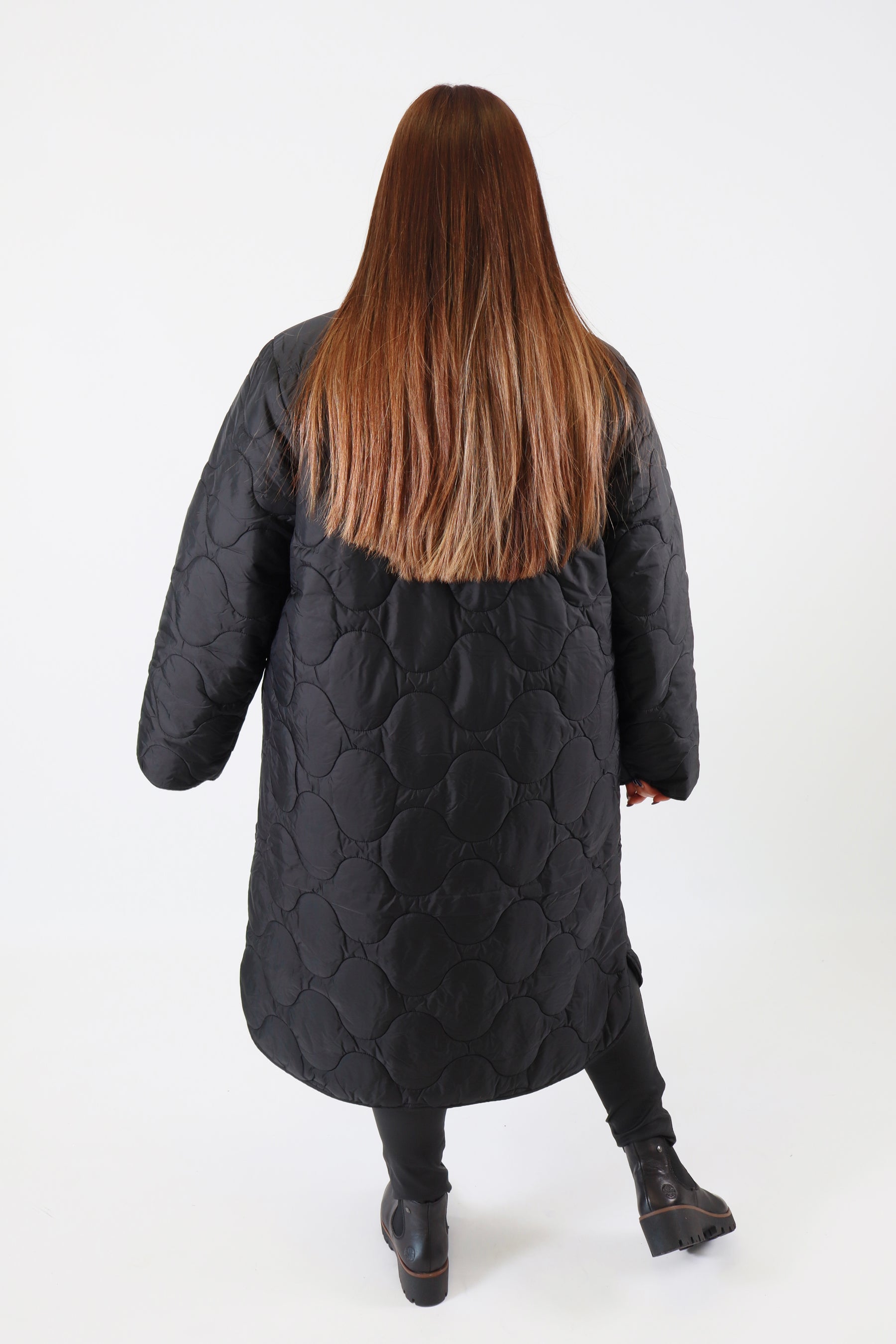 Person wearing a black coat with a plain background