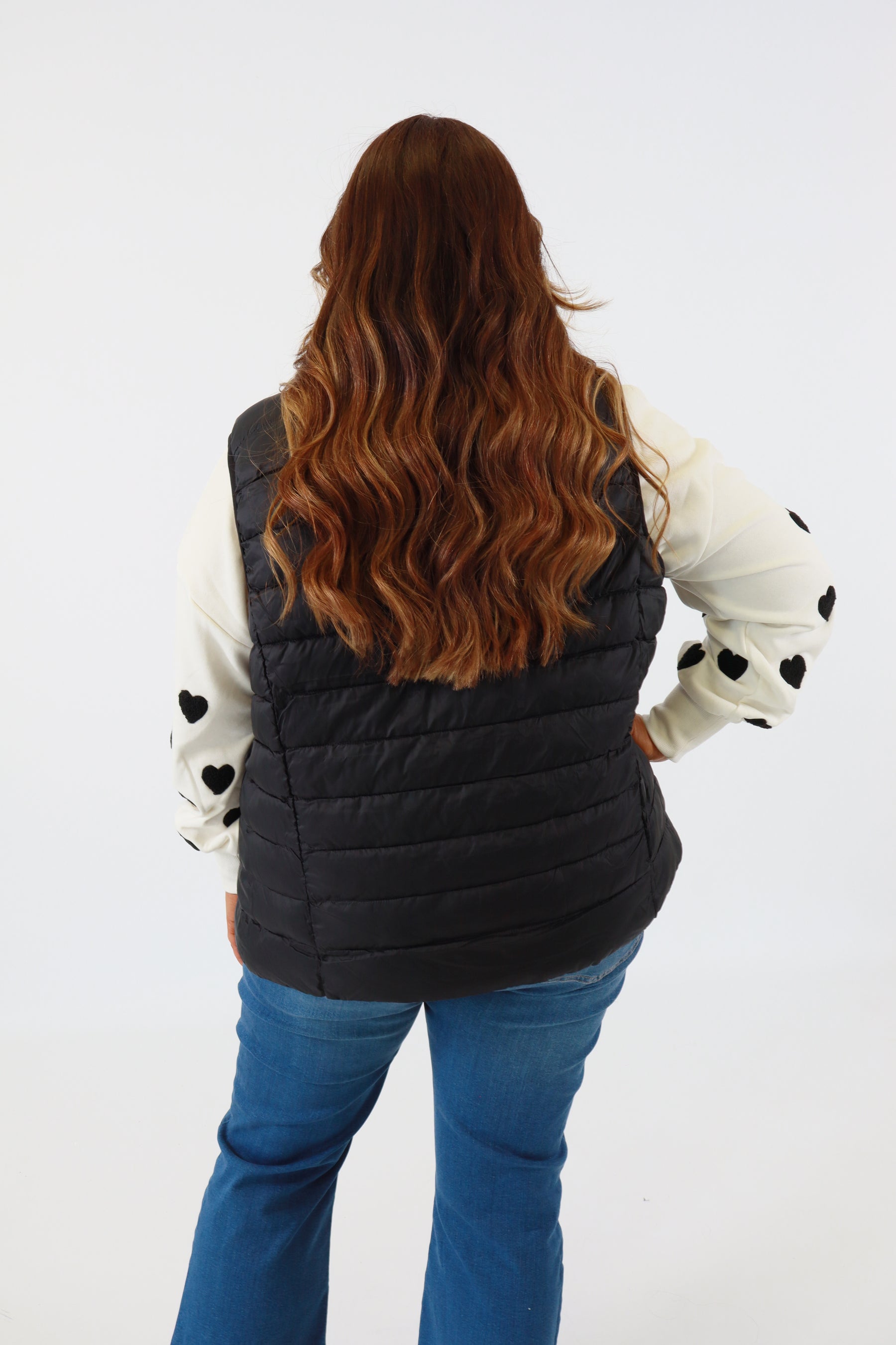 Person wearing a black oven mitt with white cuffs and black dots on a white background