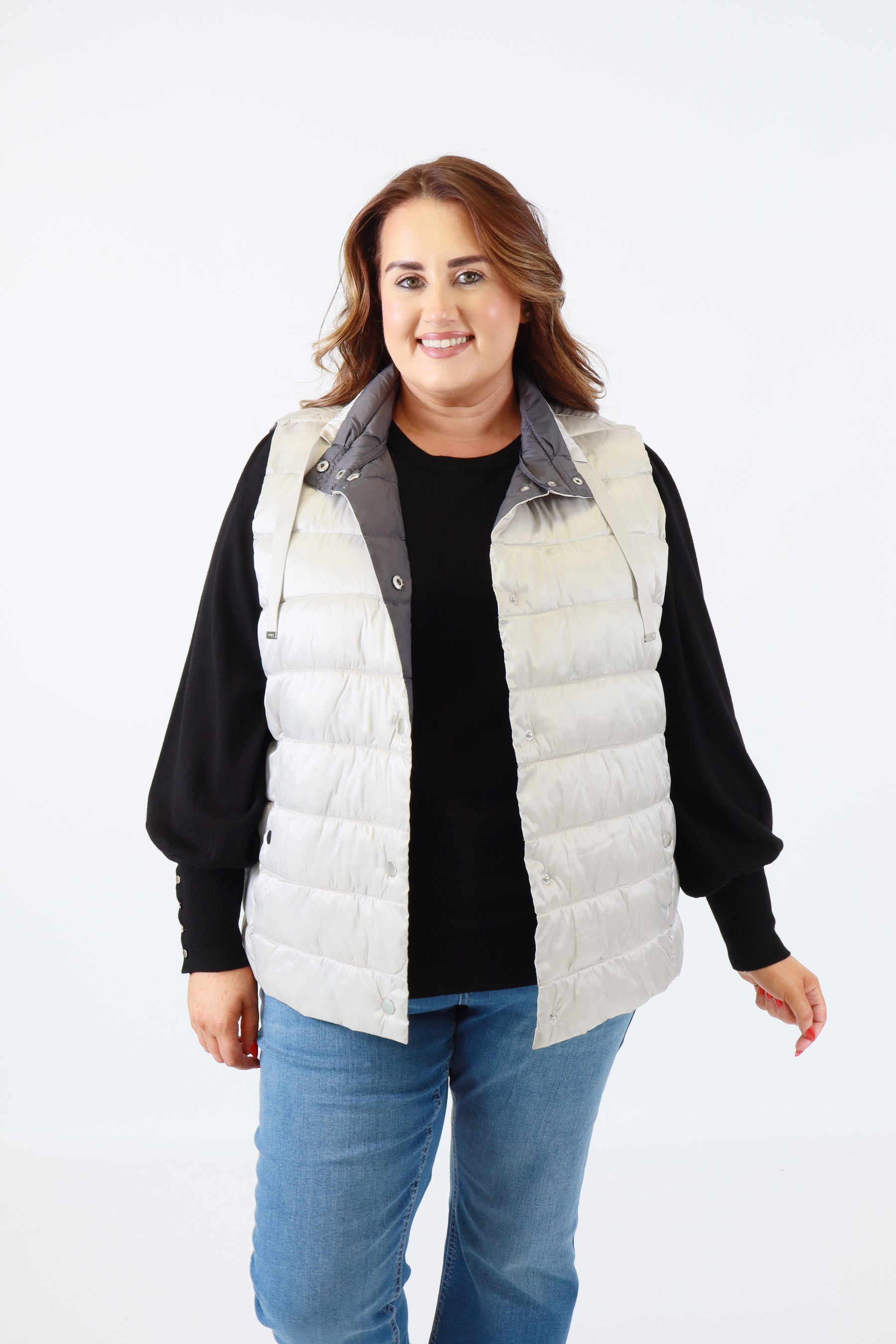 Person wearing a black sweater and white puffer vest on a white background