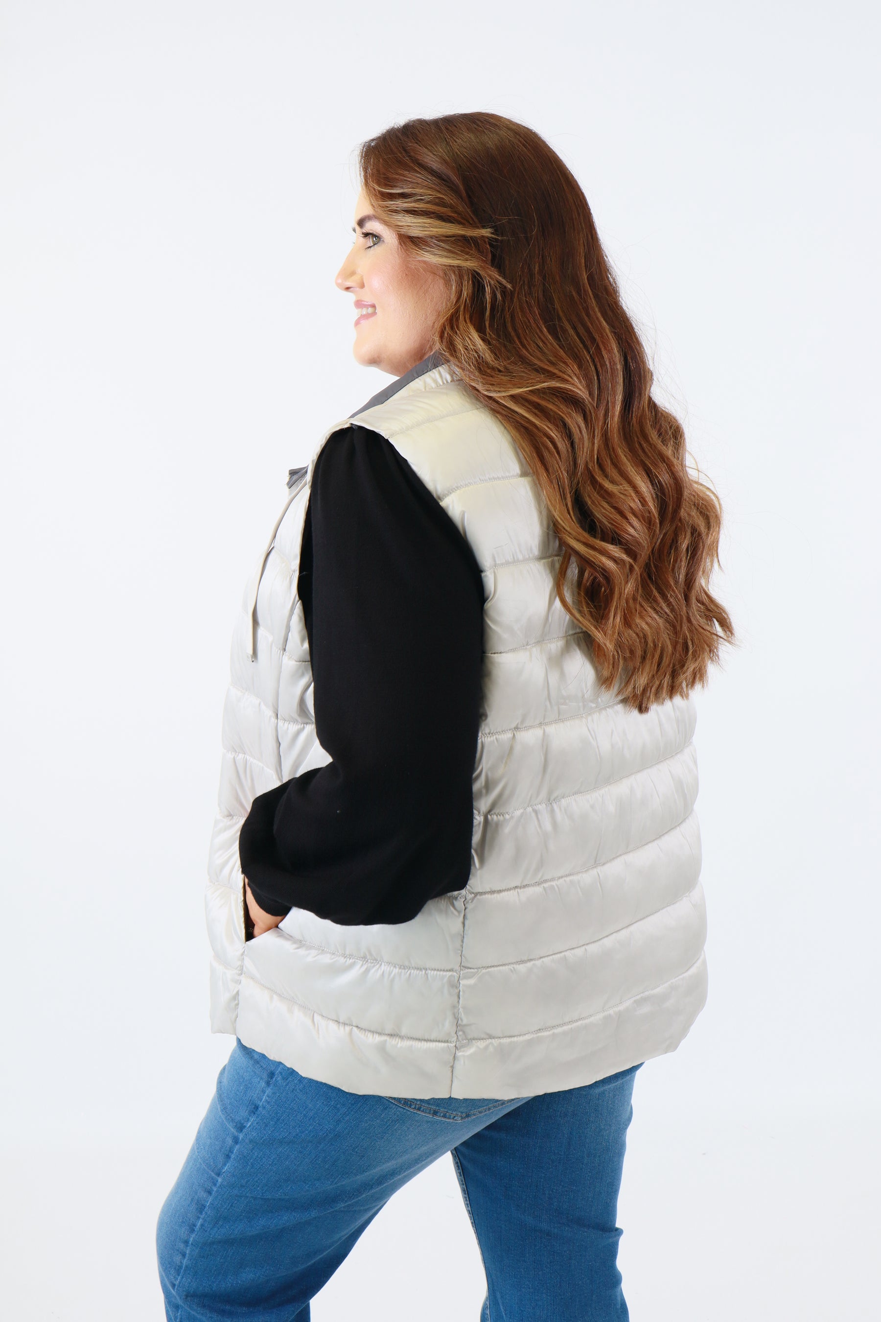 Woman wearing a silver puffer vest on a white background