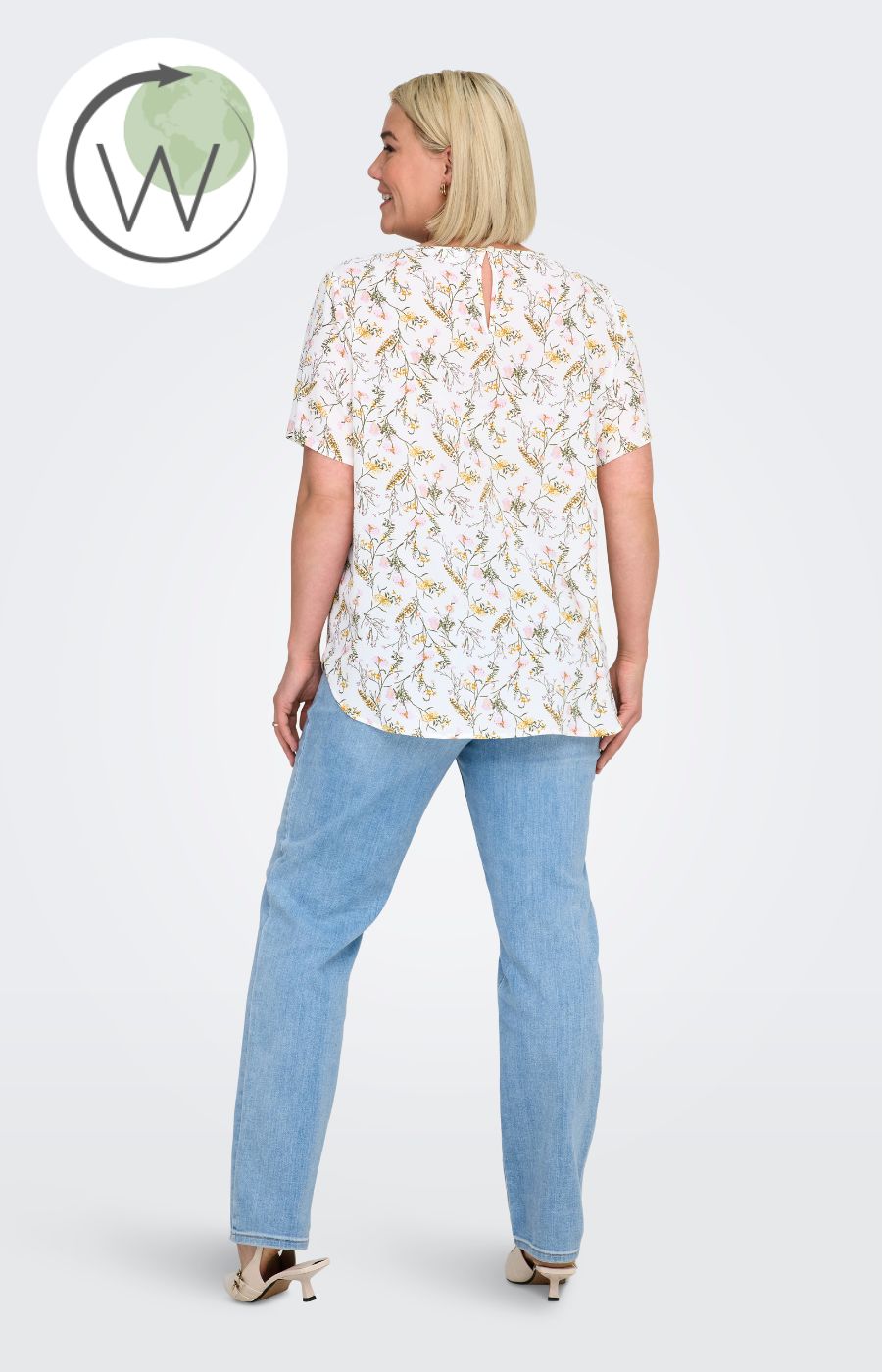 Woman wearing a white blouse, with a floral design all over and light blue jeans on a white background
