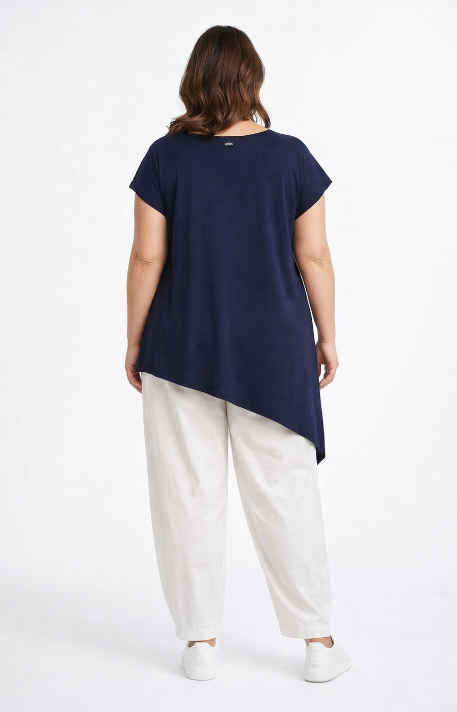 Person wearing a navy top and white pants on a white background