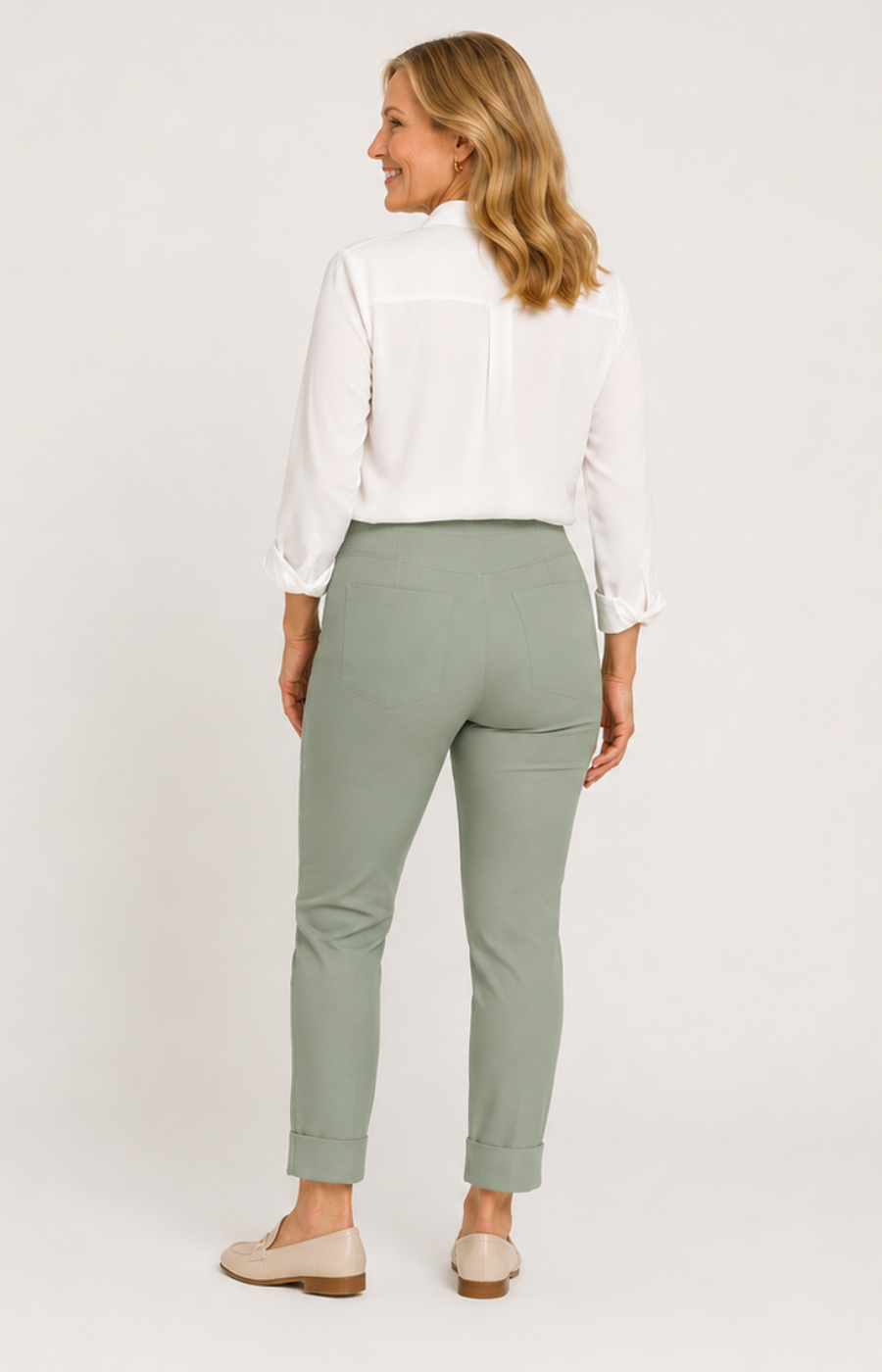 Woman wearing a white blouse and light green pants on a plain background