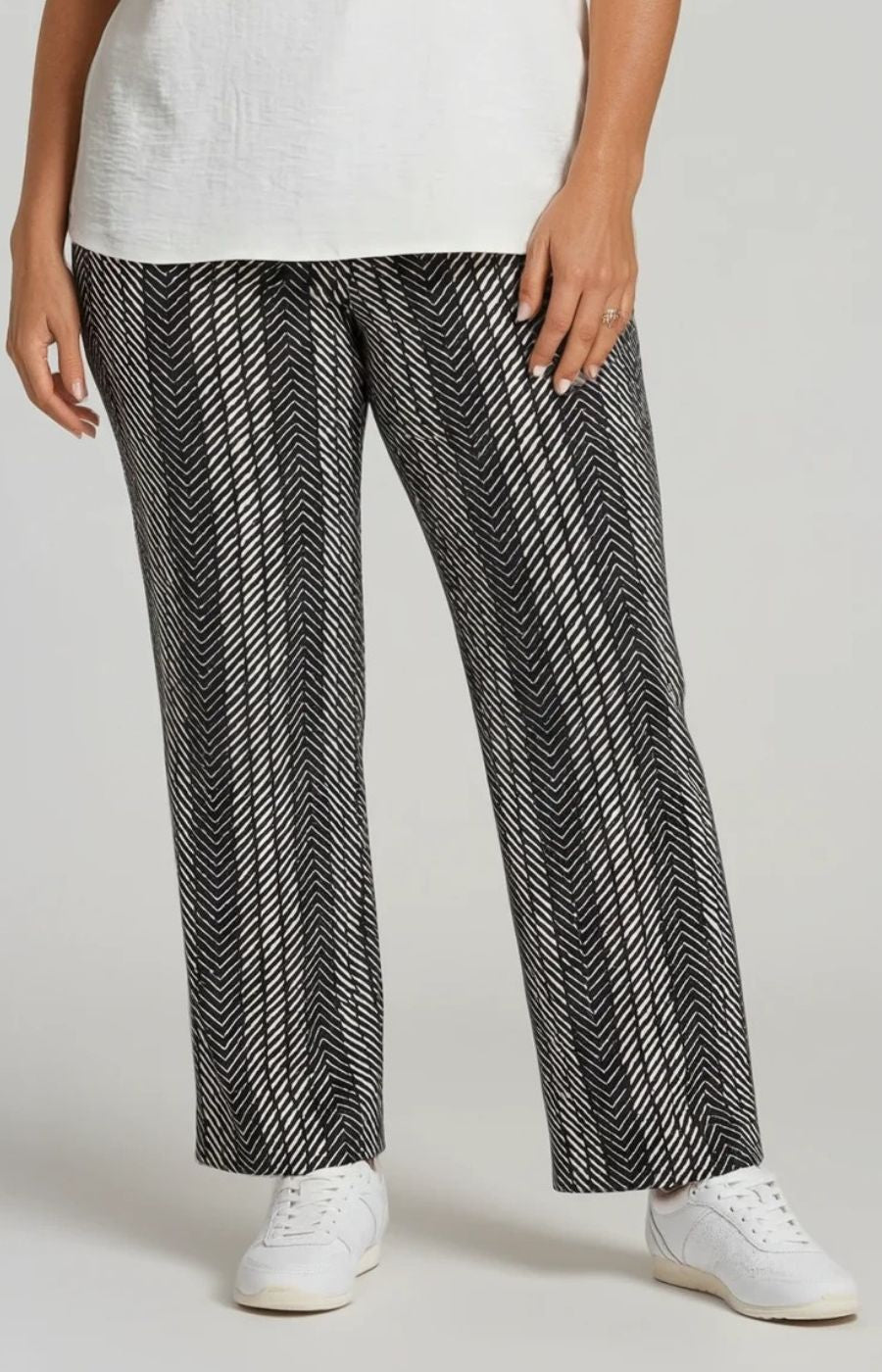 Person wearing black and white patterned pants with a plain background