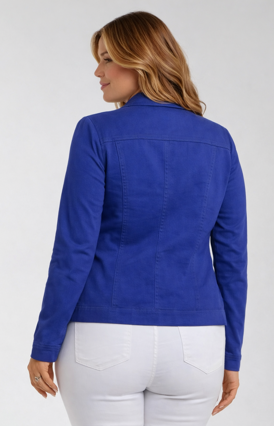 Woman wearing a blue jacket and white pants on a plain background