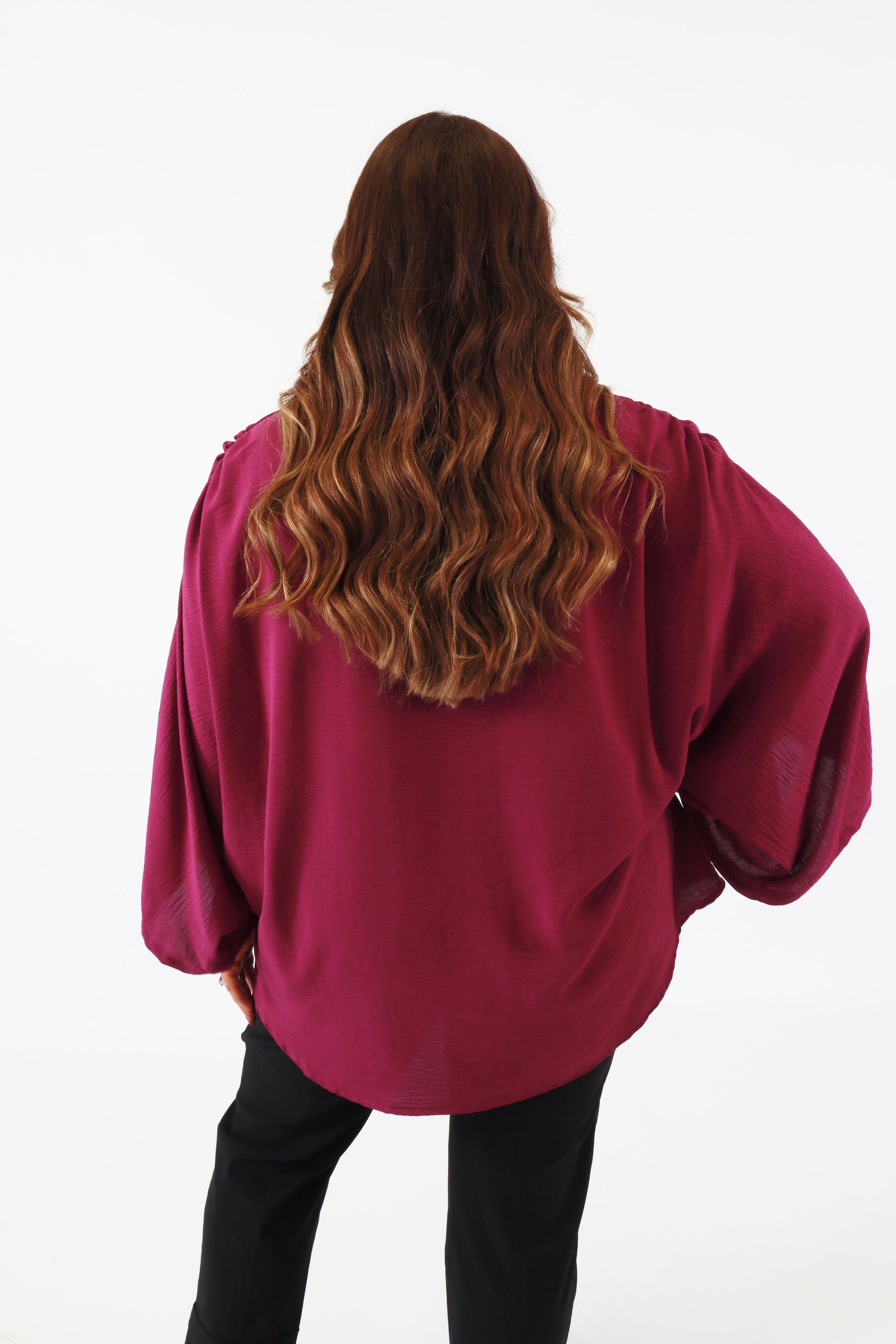 Person wearing a magenta oversized top on a white background