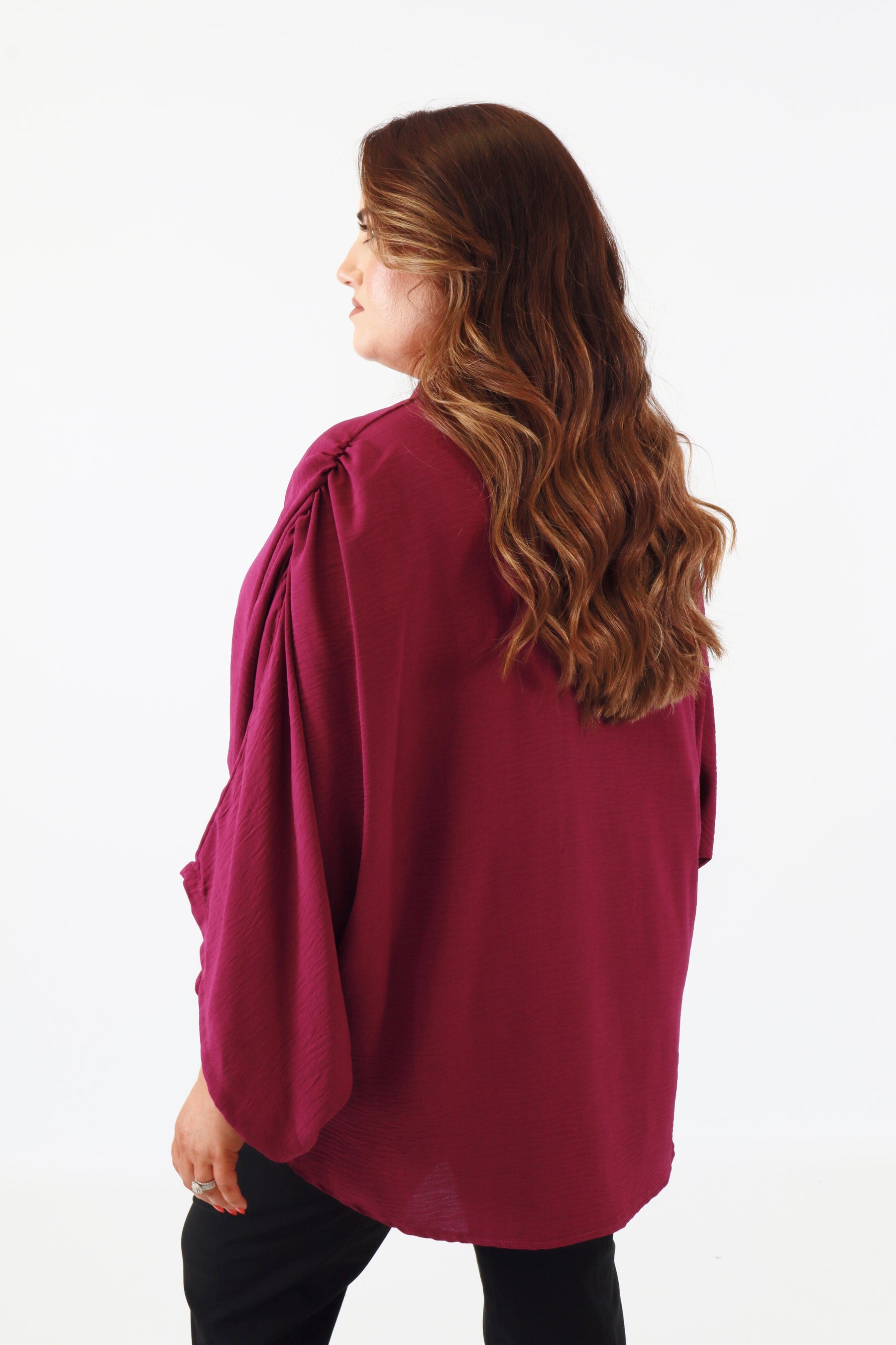 Woman wearing a magenta blouse with long sleeves on a white background