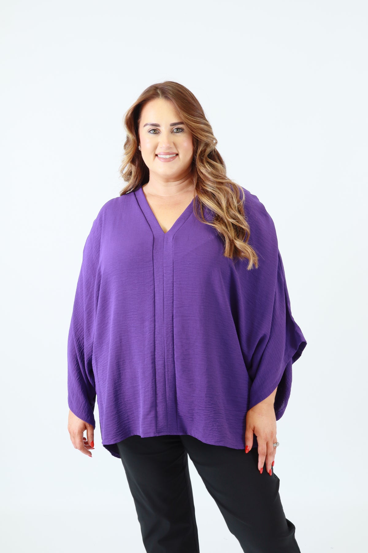 Person wearing a purple top and black pants on a white background