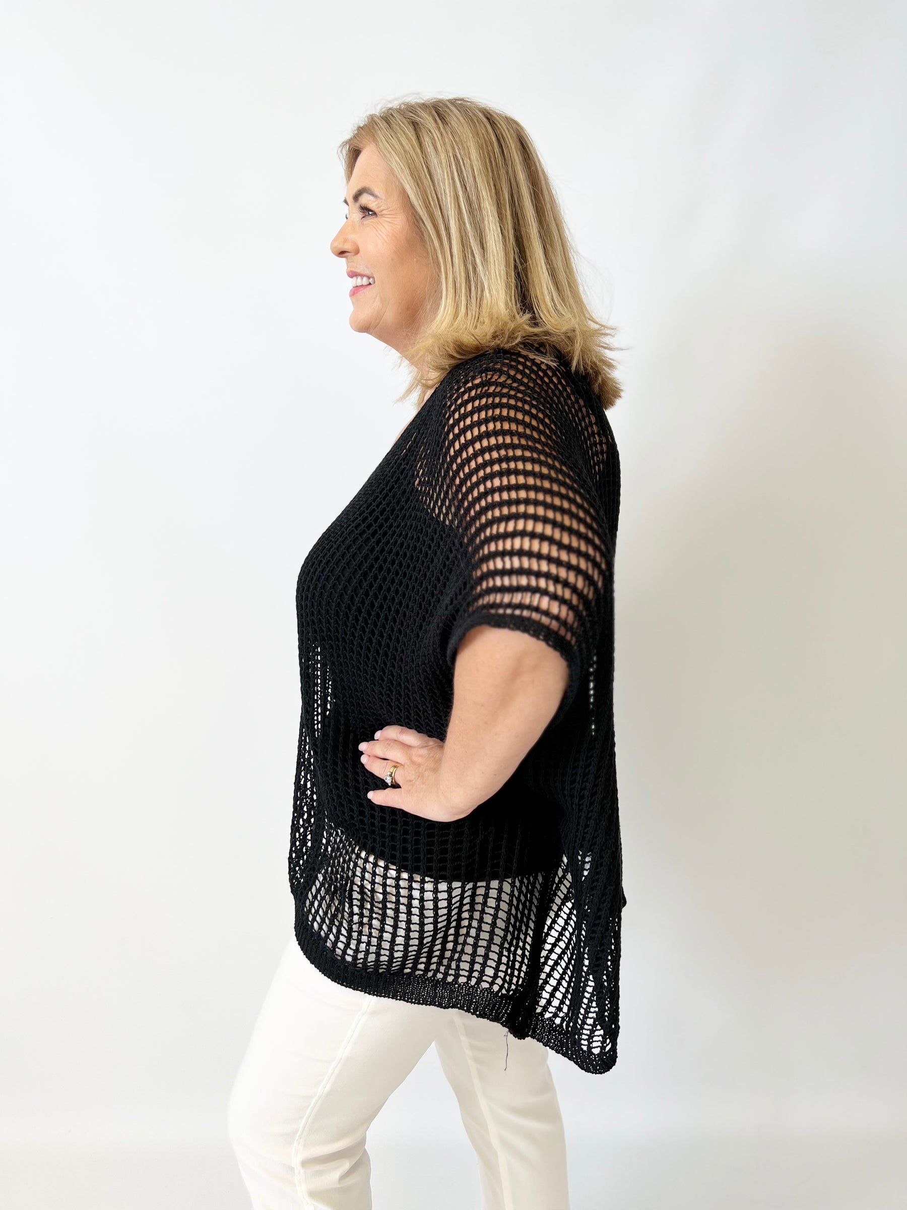 Woman wearing a black mesh top against a white background
