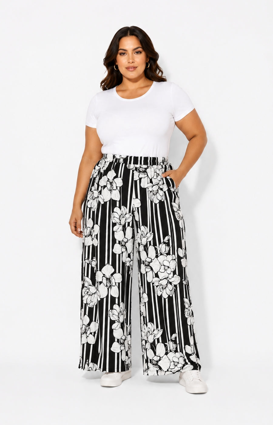 Woman wearing a white t-shirt and black and white floral wide-leg pants on a white background