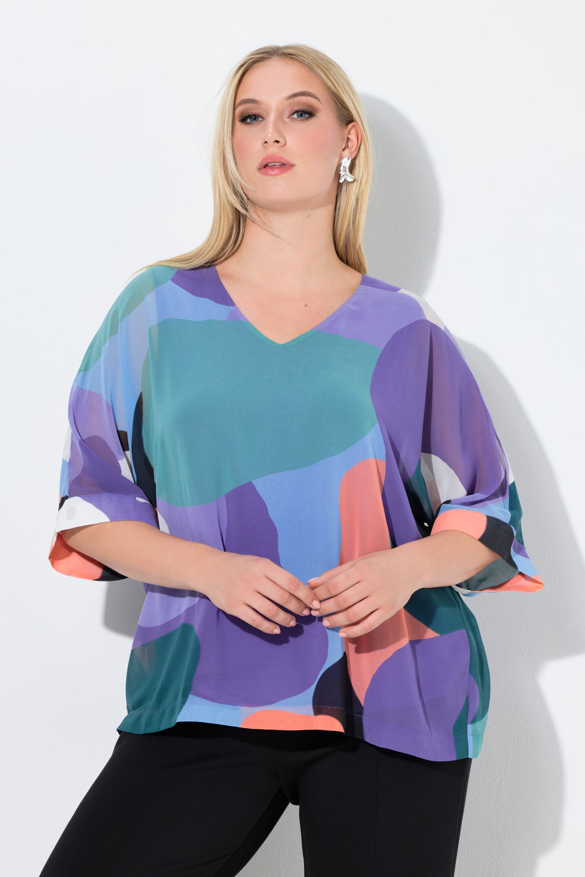 Woman wearing the Ulla Popken Multicolour Chiffon Blouse, a colorful abstract patterned top with a V neckline and 3/4 length sleeves against a white background
