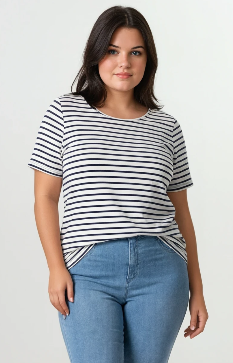 Woman wearing a black and white striped shirt and blue jeans on a plain background