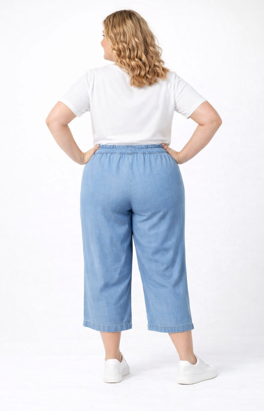 Woman wearing a white t-shirt and light blue denim pants on a white background