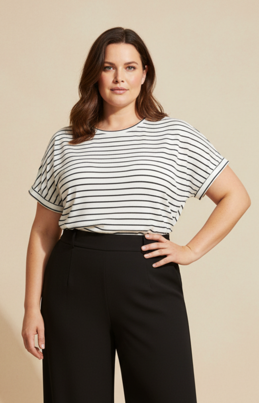 Woman wearing a black and white striped shirt and black pants on a beige background
