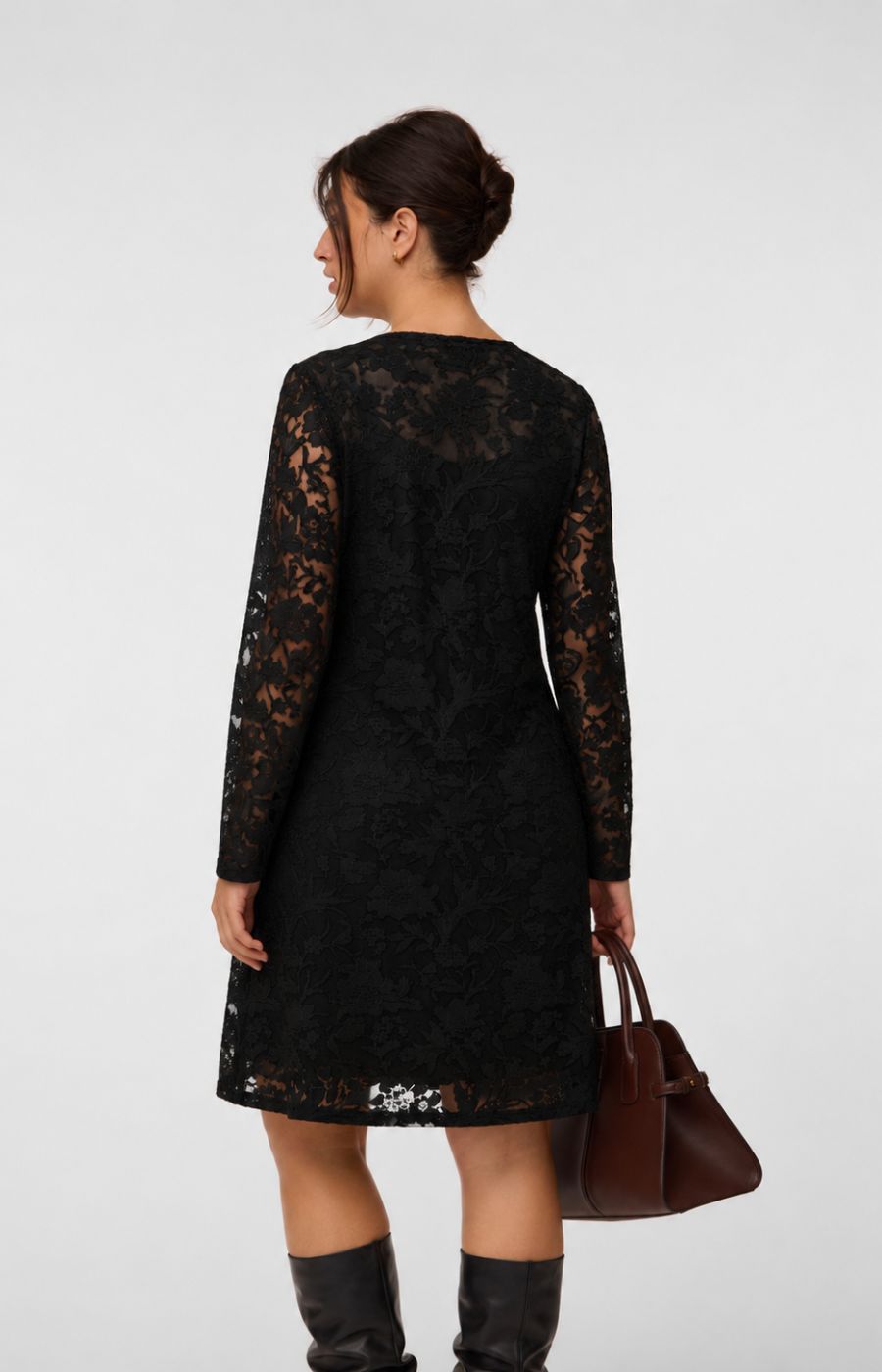 Model wearing the Vero Moda Curve Layla Dress in Black, a knee length black lace dress with a boat neckline and long sleeves. This image was created using AI