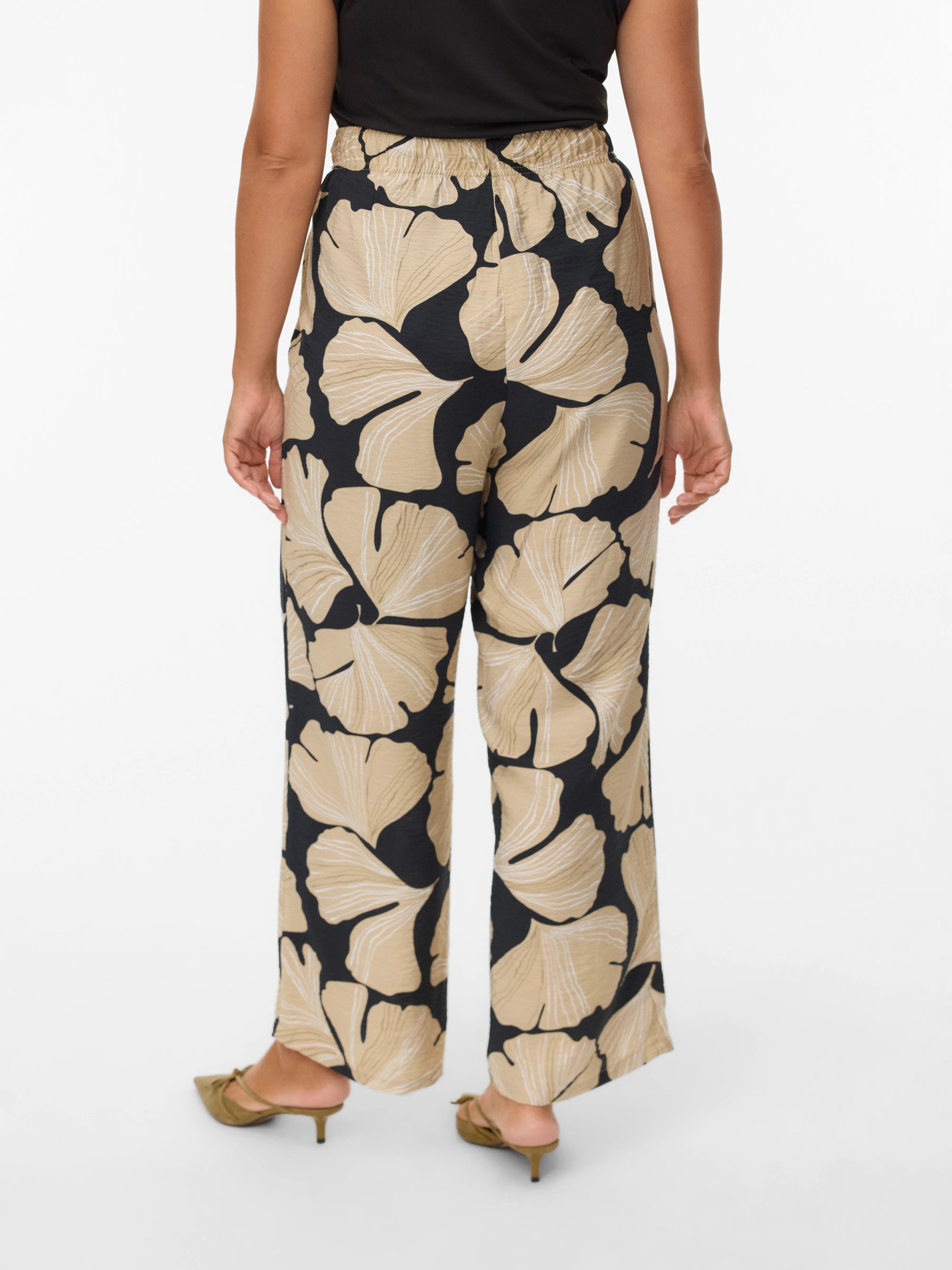 Woman wearing a black and beige floral patterned pants on a white background