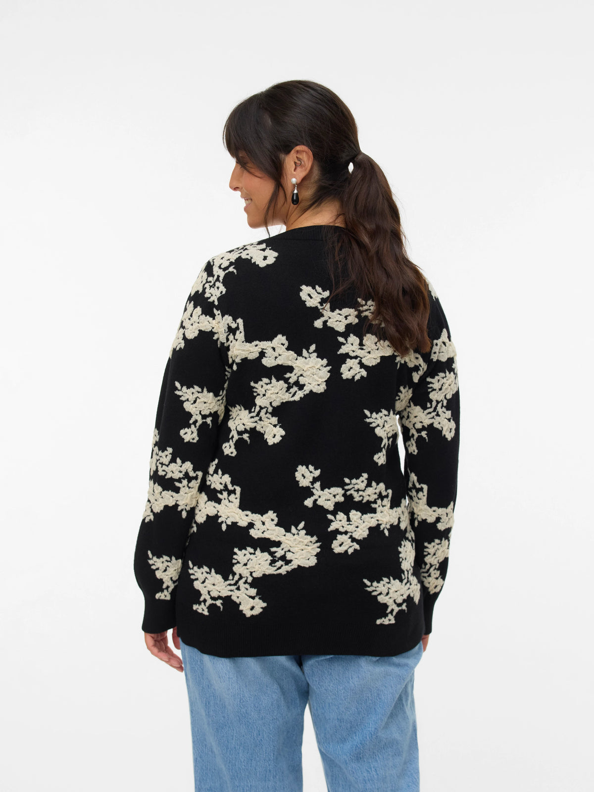 Person wearing a black sweater with white floral patterns on a white background