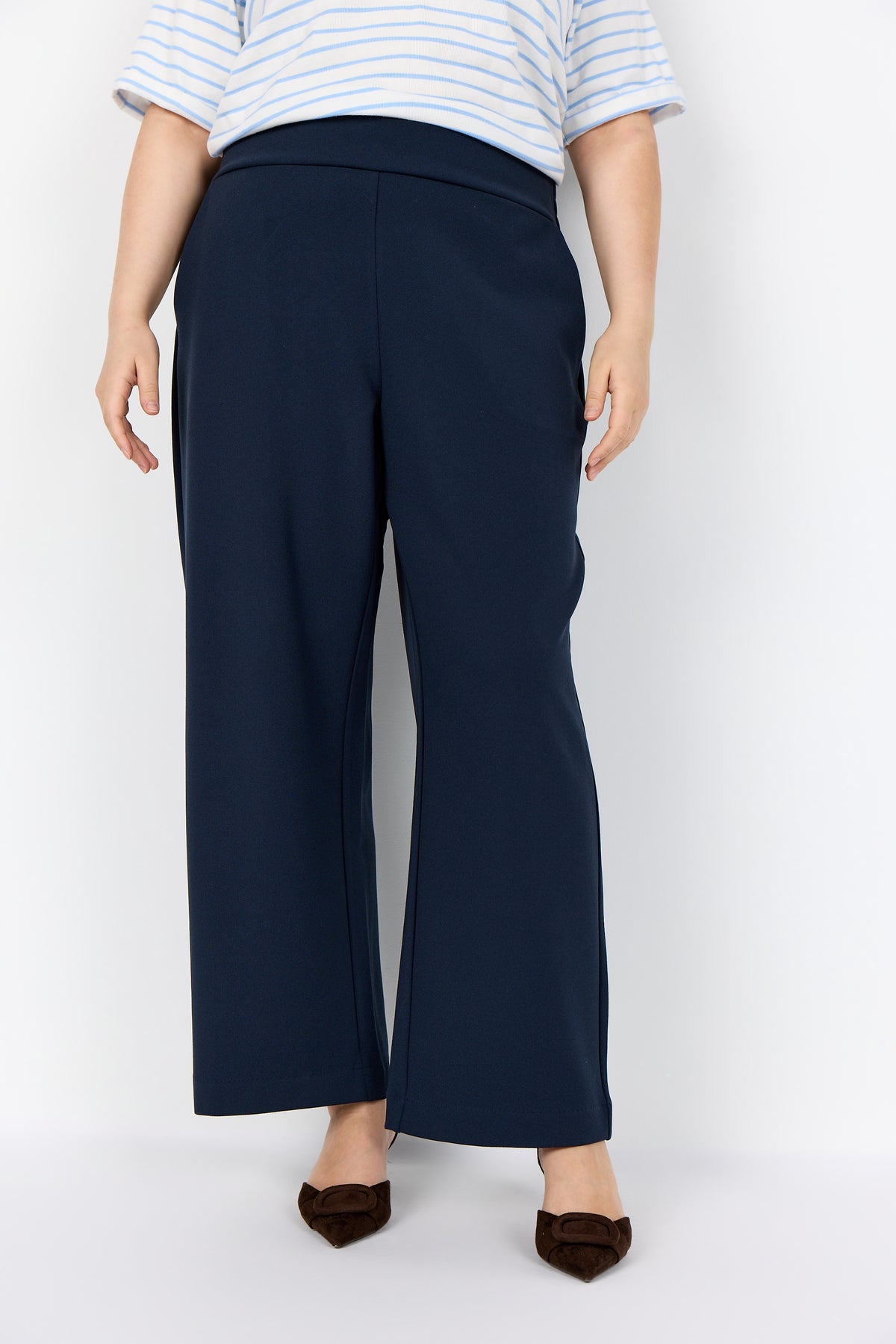 Person wearing the Wasabi Kufa Trousers in Navy, a navy wide-leg trousers and a striped shirt on a white background