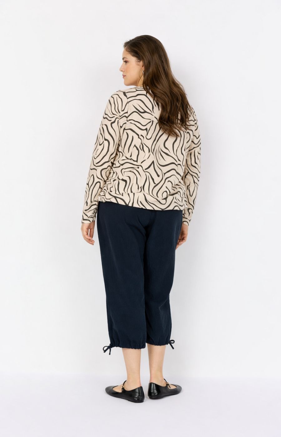 Woman wearing a Wasabi Saliha Blouse in Cream and navy pants on a white background